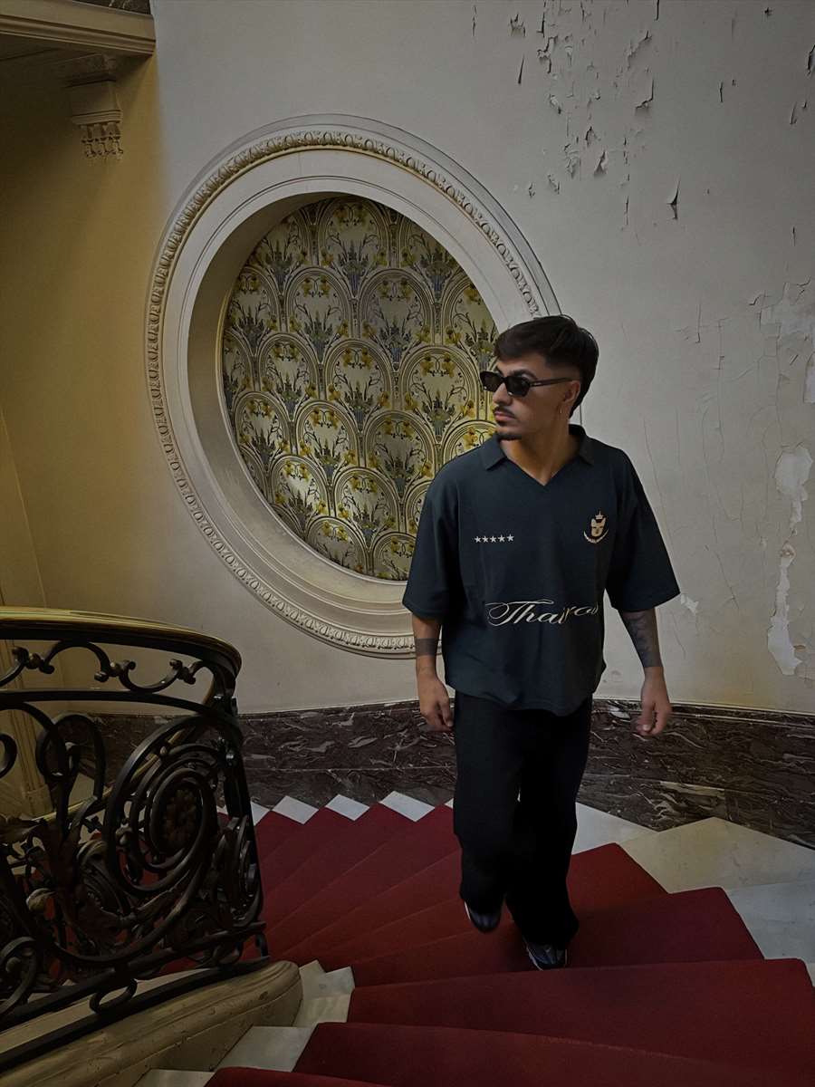 Polo Thairos verde en una escalera con alfombra roja.