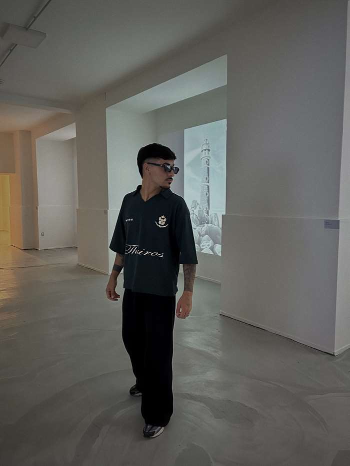 Polo Thairos en una sala blanca, con una proyección de fondo.